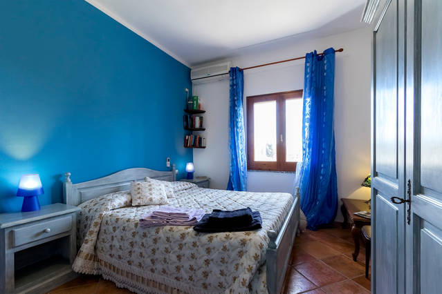 Camera matrimoniale con parete blu e luce naturale Camera matrimoniale con parete blu, ampia finestra e arredamento classico