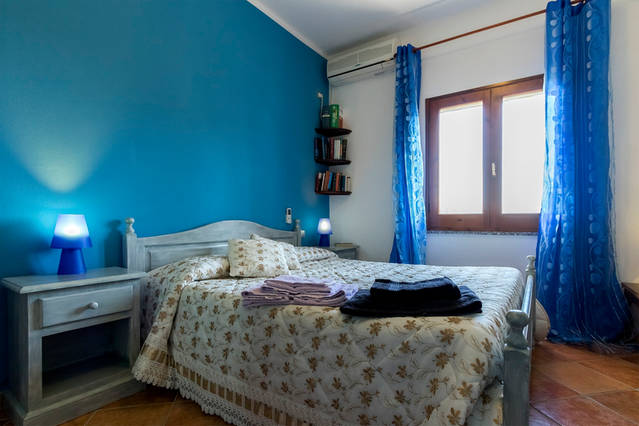 Camera matrimoniale con pareti blu e arredi rustici