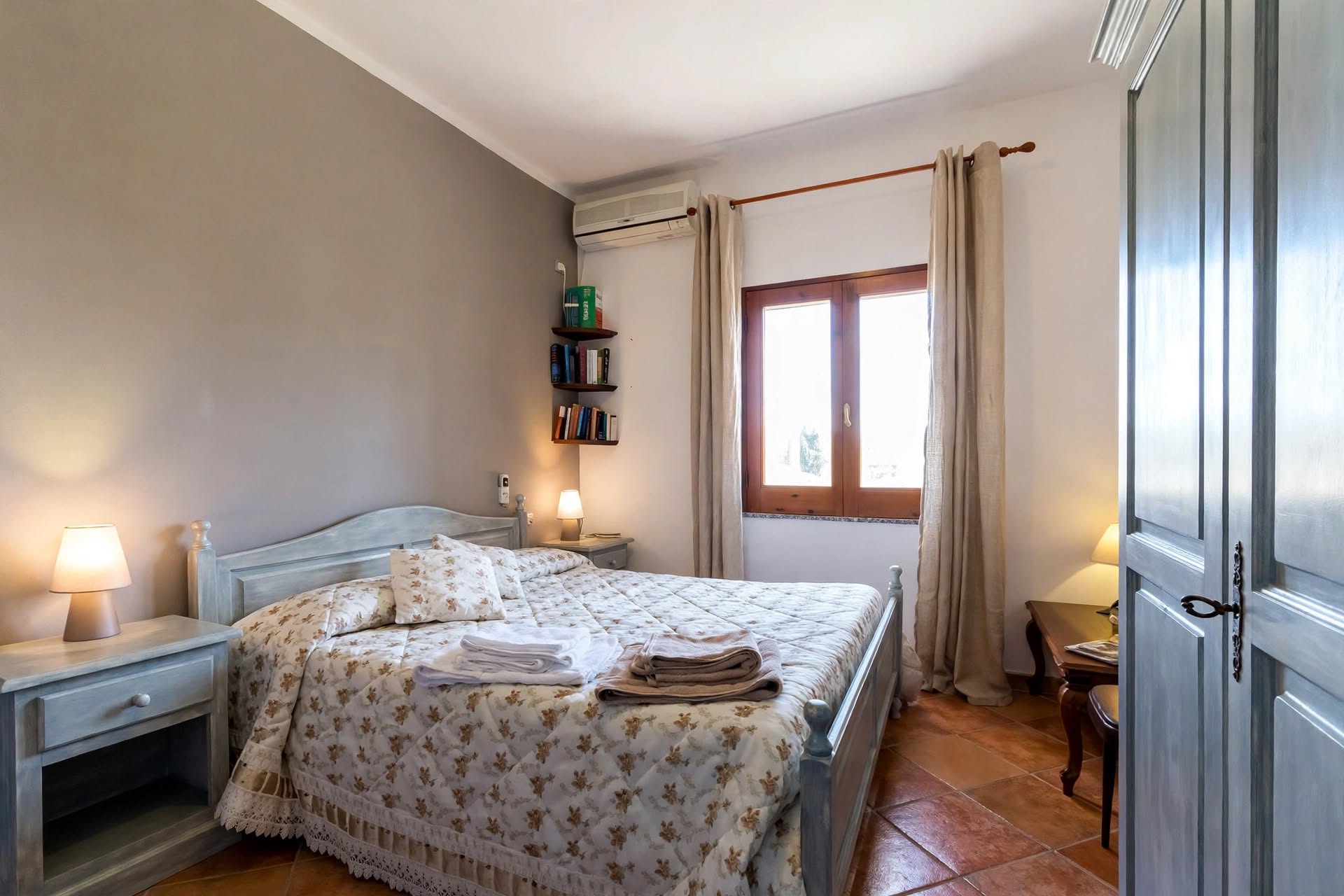 Camera matrimoniale con parete blu, ampia finestra e arredamento classico