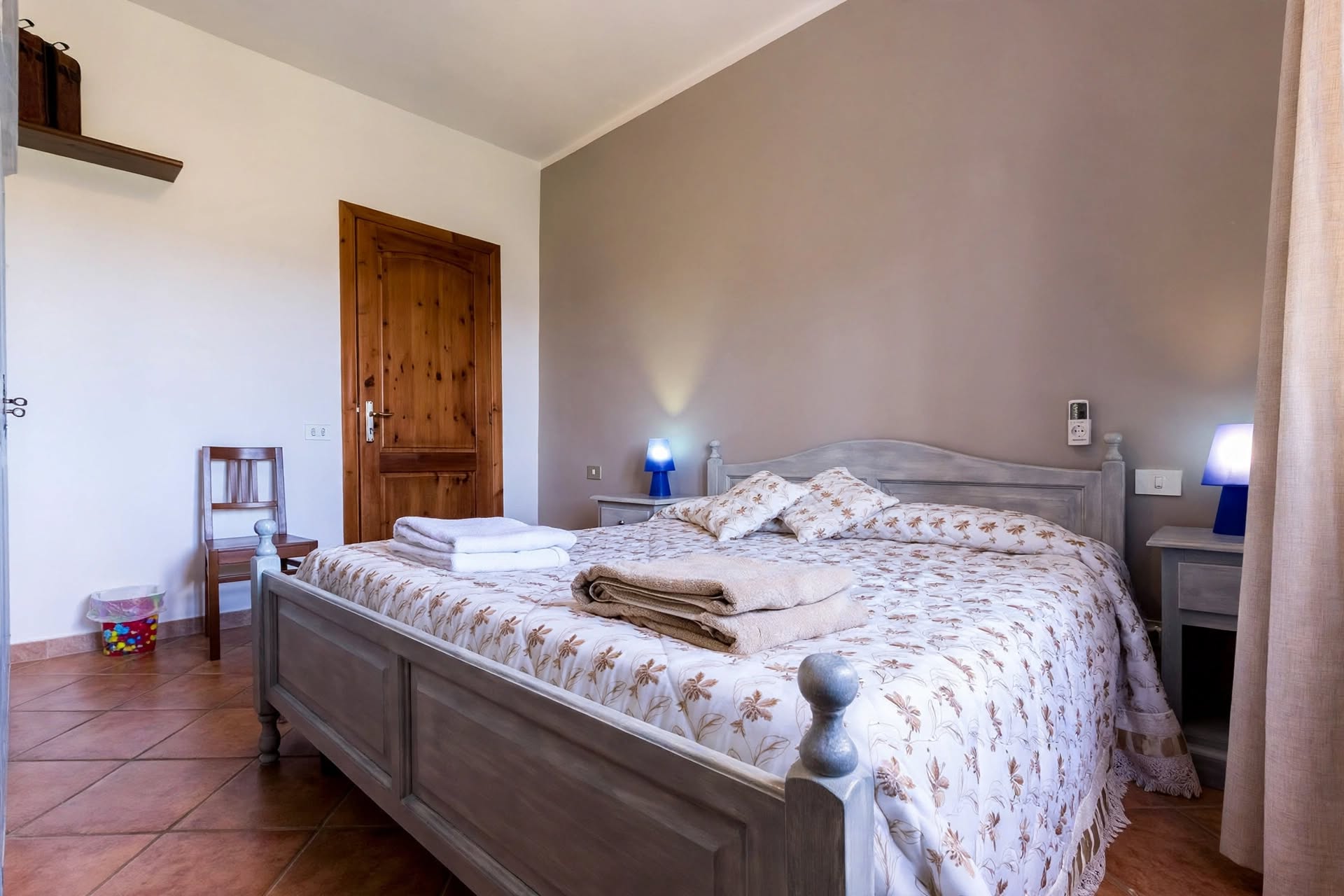Camera matrimoniale con pareti blu mare, letto matrimoniale e due lampade da comodino